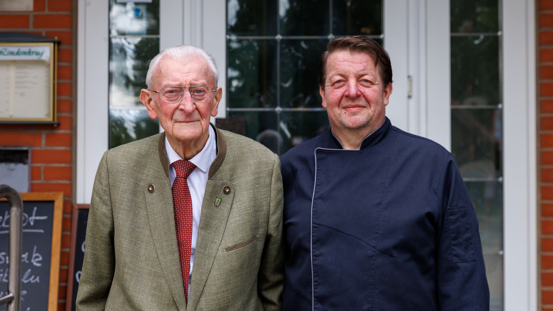Heinrich und Thorsten Löding_Zum Lindenkrug Witzeeze Bild von einem älteren und einem jüngeren Mann vor einer Gaststätte