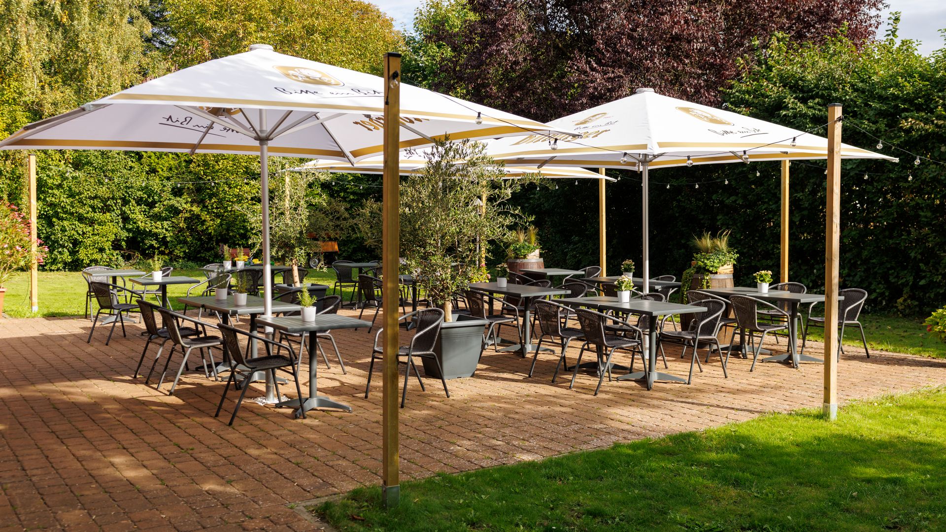 Terrasse Patchwork im Landhaus Köthel Terrasse mit großen Schirmen, Tischen und Stühlen.