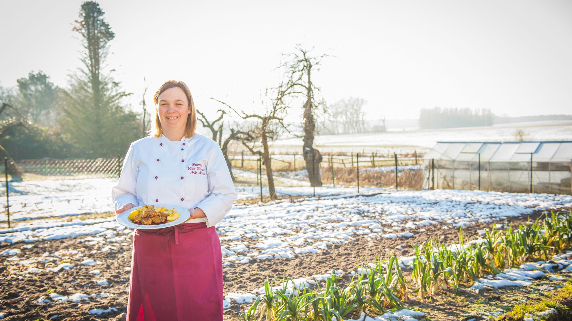 Frau im Garten mit einem Teller mit Essen in der Hand.