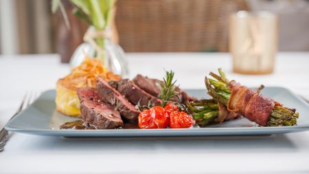 Ein Tellergericht mit Wildfleisch steht auf einem Tisch.