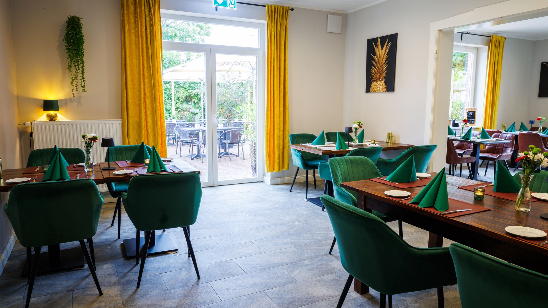 Gastraum Patchwork Landhaus Köthel Schön gedeckte Tische mit Stühlen in einem Restaurant mit Blick durch eine Tür im Hintergrund.