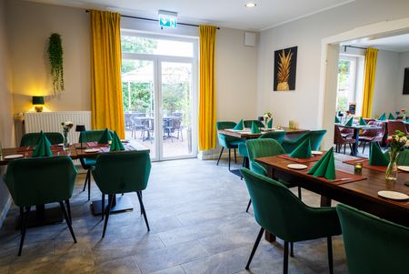 Schön gedeckte Tische mit Stühlen in einem Restaurant mit Blick durch eine Tür im Hintergrund.