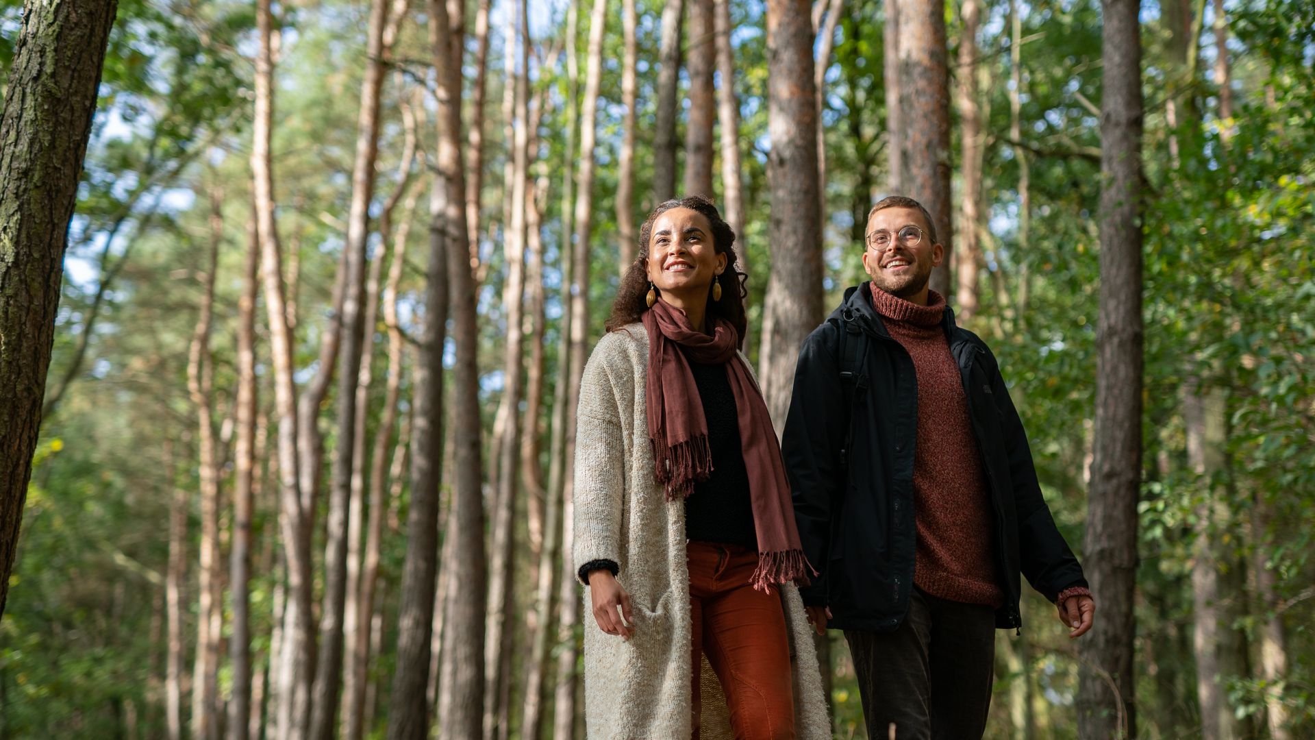 herbstlich gekleidetes Paar beim Spaziergang im Wald